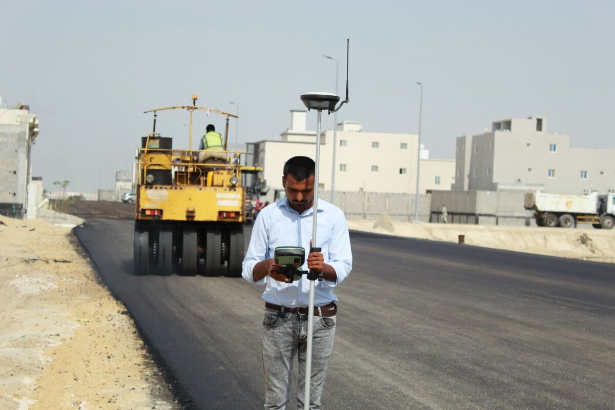 Surveyor using a GNSS RTK rover on a road construction site in Al Khobar